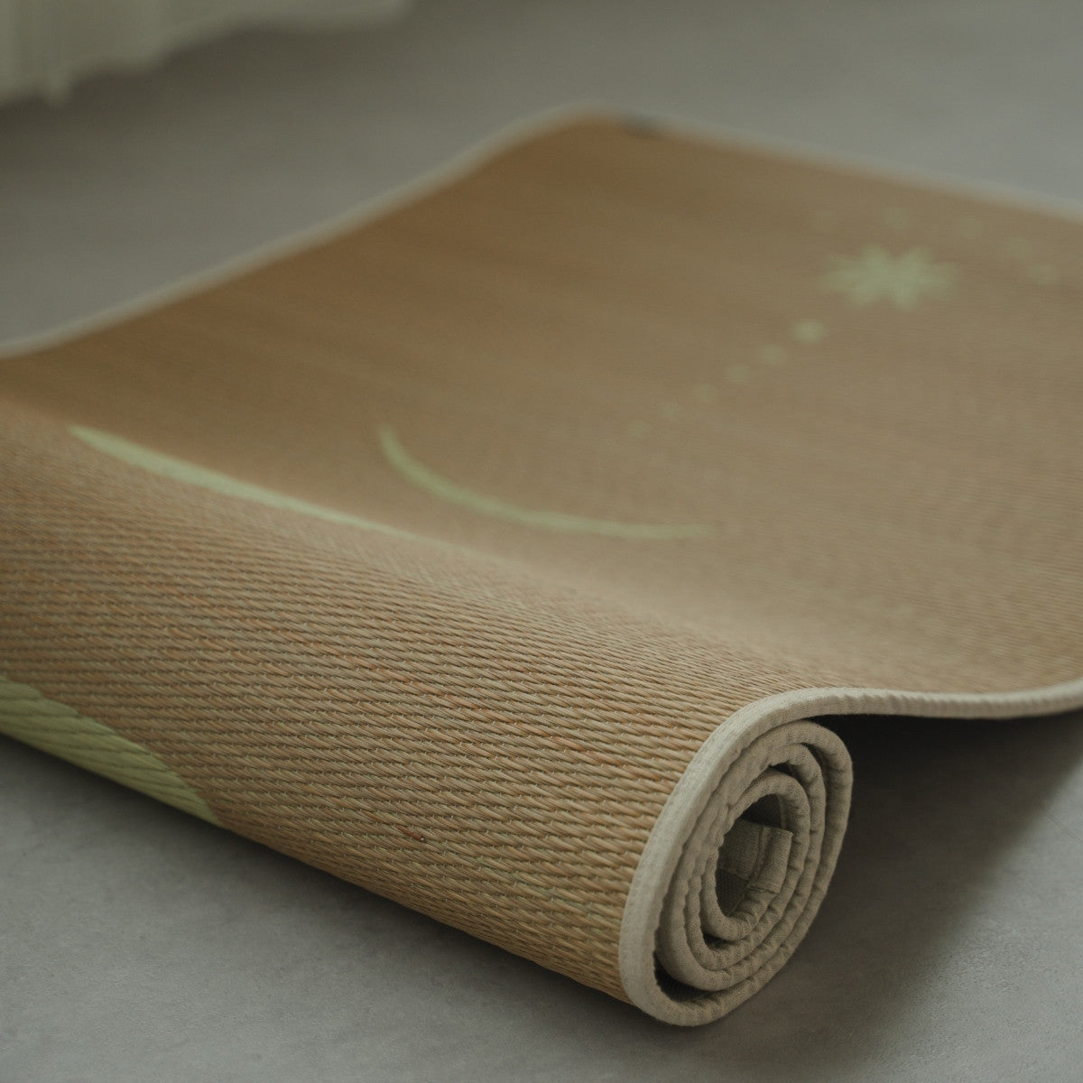 Japanische Tatami-Yogamatte „Mond“ Beige, teilweise auf einem grauen Boden aufgerollt, zeigt die feine Textur des natürlichen Binsengrases.