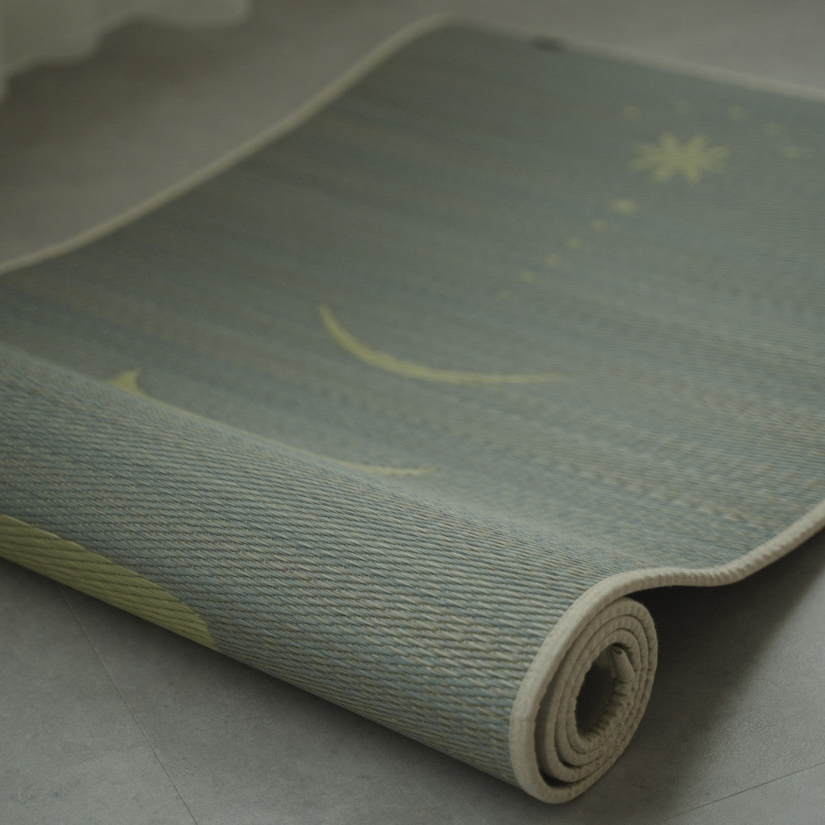 Graue japanische Tatami-Yogamatte „Mond“, teilweise auf einem Betonboden gerollt, die die feine, authentische Textur von gewebtem natürlichem Binsenstroh zeigt.