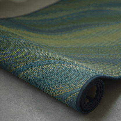 Japanese Tatami Yoga Mattress "Marble" Blue partially rolled on a grey floor, revealing the natural rush grass weave.