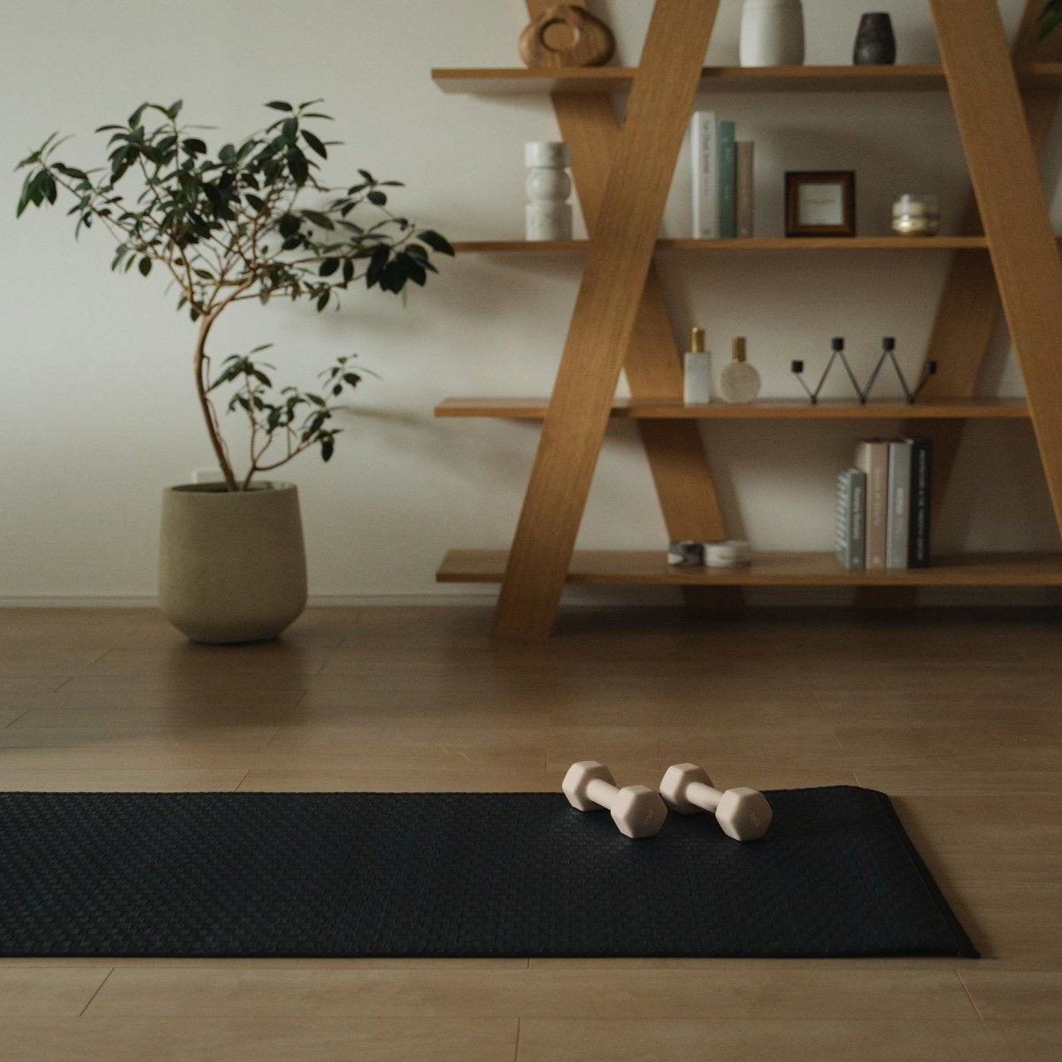 Japanese Tatami Yoga Mattress "Ed Plain" Navy with dumbbells in a minimalist Japandi living room for daily home yoga routines.