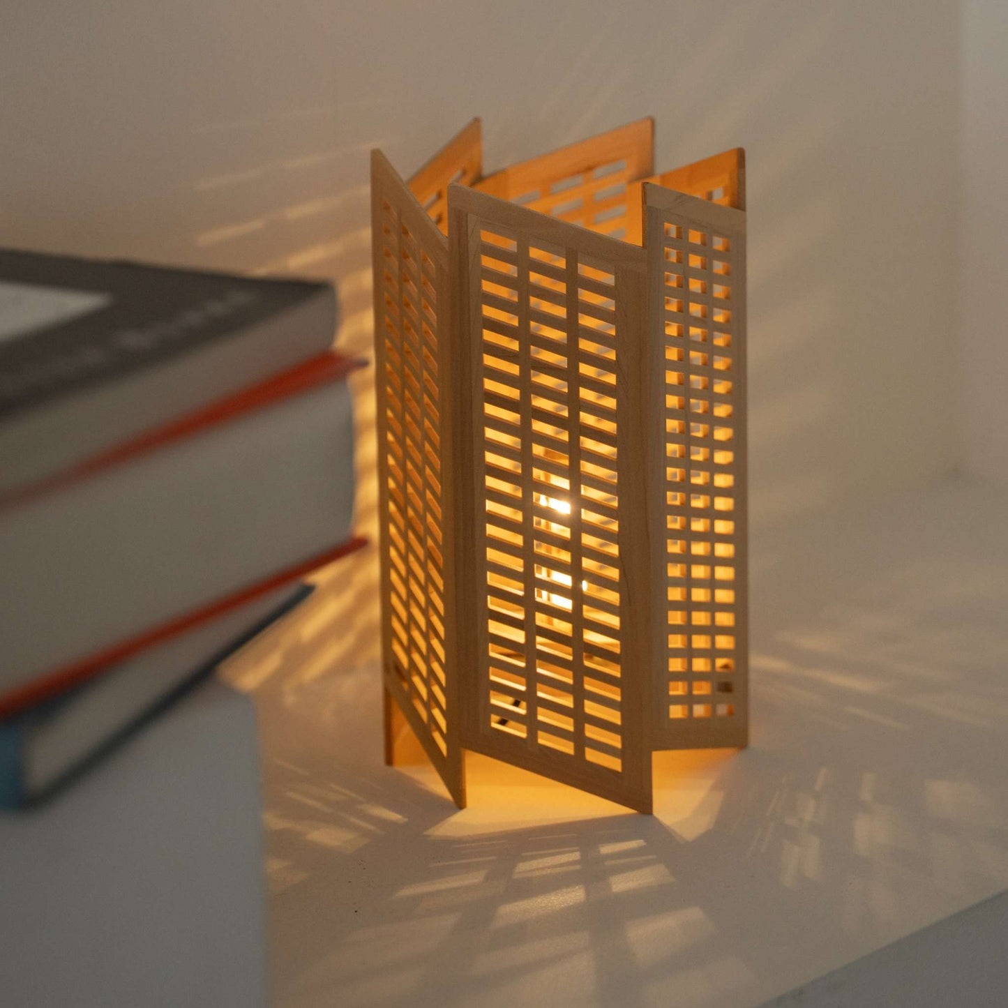 "Lampe d'appoint japonaise en bois \"Towaru\", créant une ambiance chaleureuse et projetant des motifs d'ombre saisissants sur la console du salon de style Japandi"
