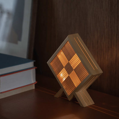 Lampe de table japonaise en bois "Kanata" projetant une forme en X lumineuse comme lampe d'ambiance sur une console de style moderne mid-century.