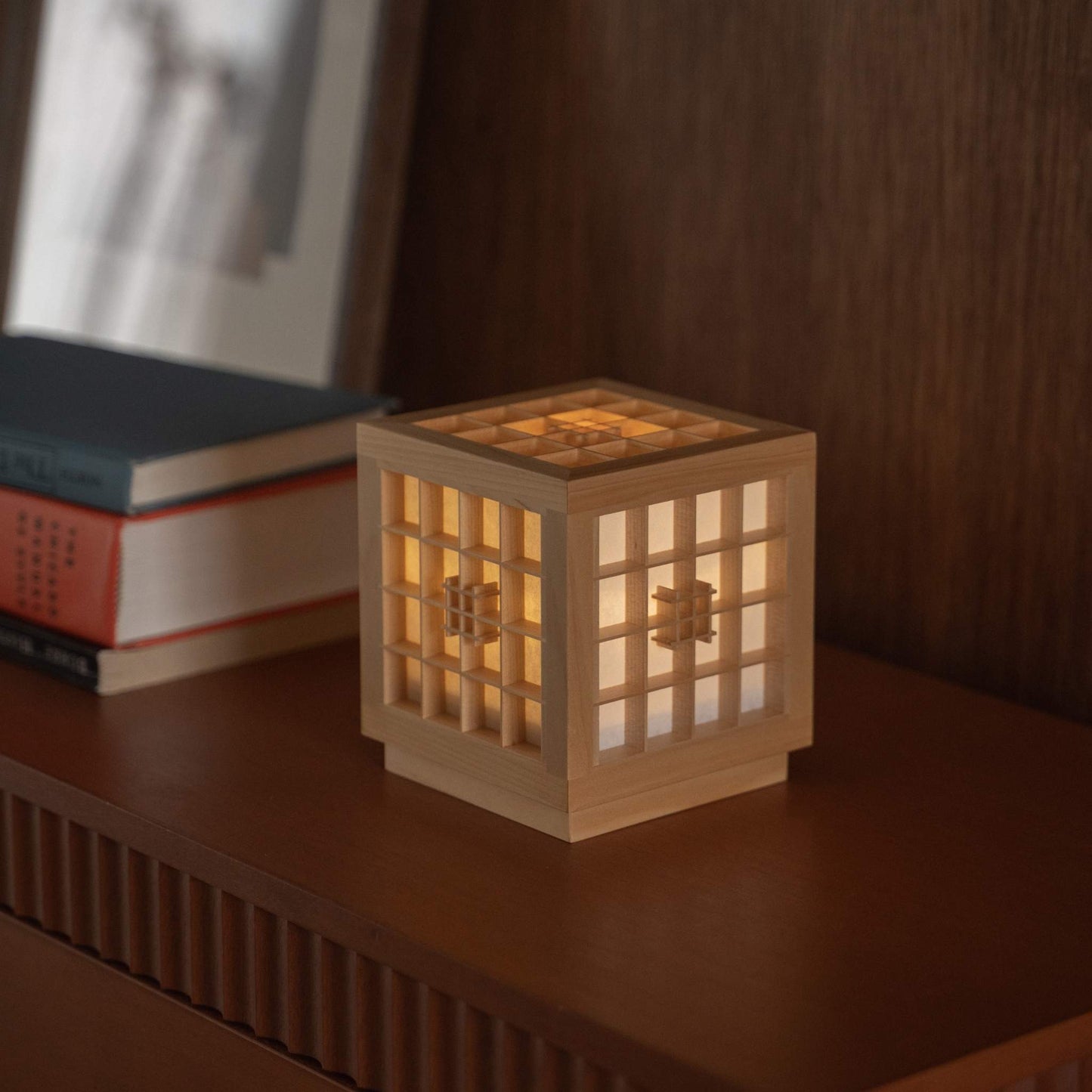 "Lampe de table japonaise lumineuse en bois « Honoka » servant de lampe d'ambiance chaleureuse à côté de livres sur une console en bois."