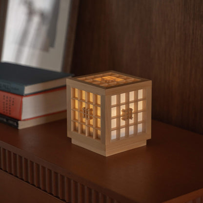 "Lampe de table japonaise lumineuse en bois « Honoka » servant de lampe d'ambiance chaleureuse à côté de livres sur une console en bois."