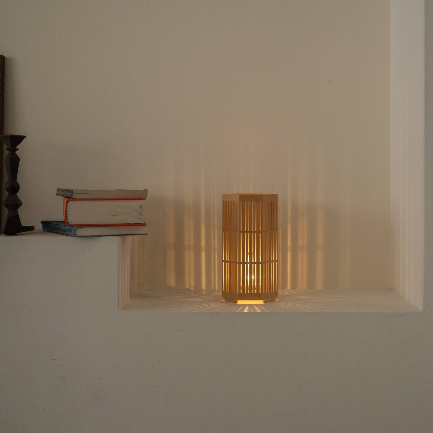 "Lampe de table japonaise en bois « Kagayaki » projetant de magnifiques ombres radiales comme lampe d'appoint wabi sabi dans un salon Japandi."