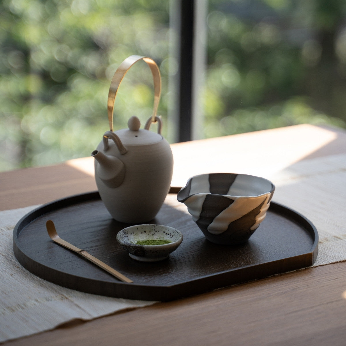 White Flow Japanese matcha bowl with spout and teapot on a wooden tray by a window, for an authentic matcha latte routine