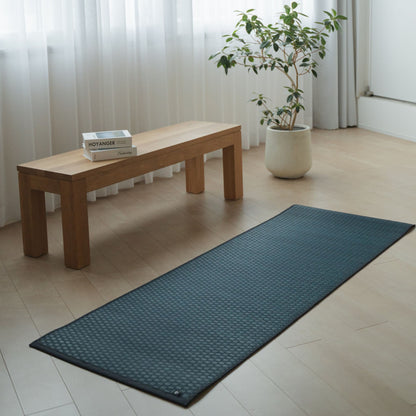 Japanese Tatami Yoga Mattress "Ed Plain" Navy unrolled on a wooden floor in a minimalist living room for a serene home practice.