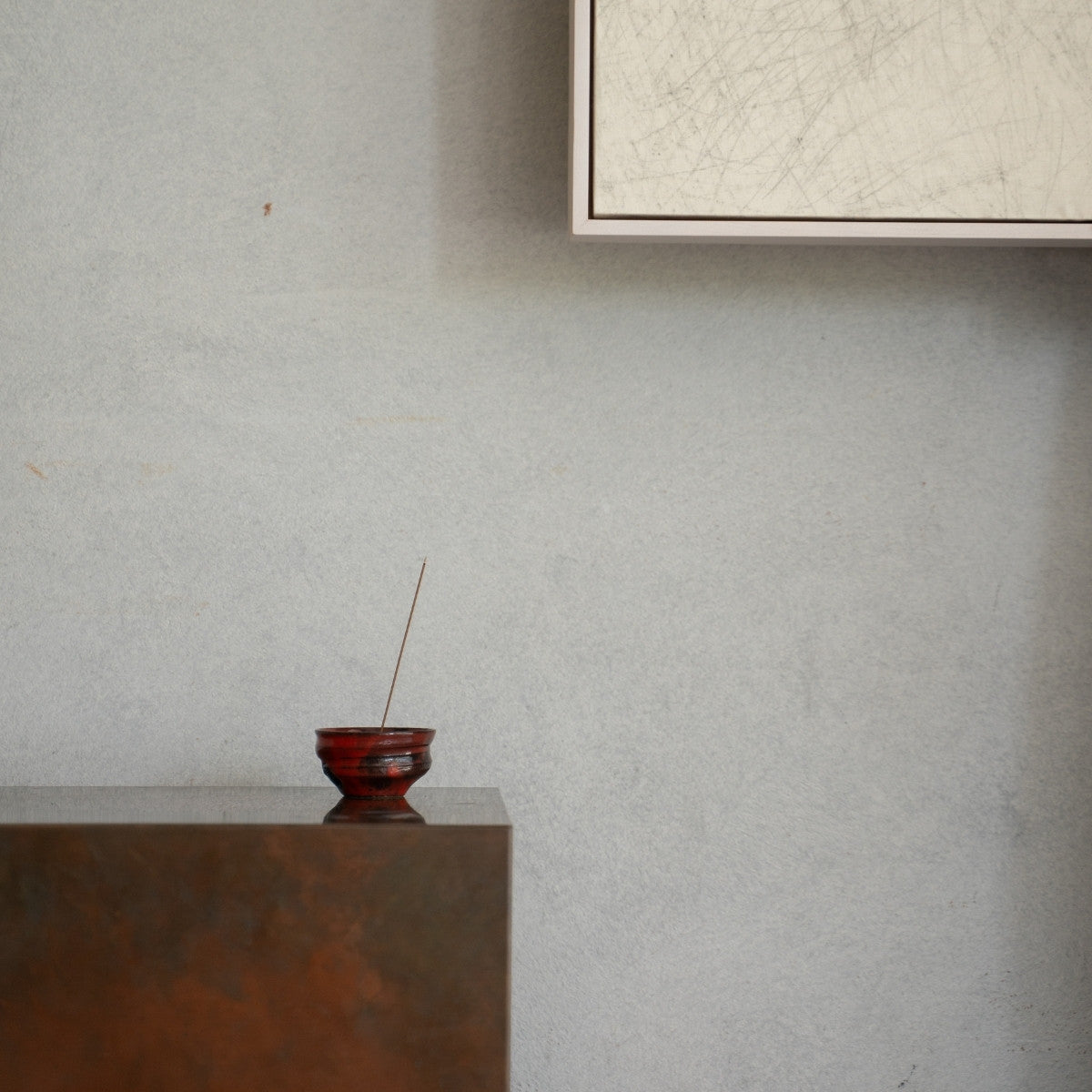 Crimson red Japanese incense burner with a lit stick on a dark console, bringing deep serenity to a daily yoga practice.