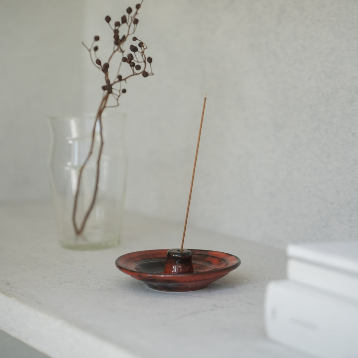 Crimson red Japanese incense holder on a dark wooden console, bringing serenity to a daily yoga practice.