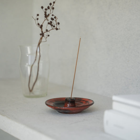 Crimson red Japanese incense holder on a dark wooden console, bringing serenity to a daily yoga practice.