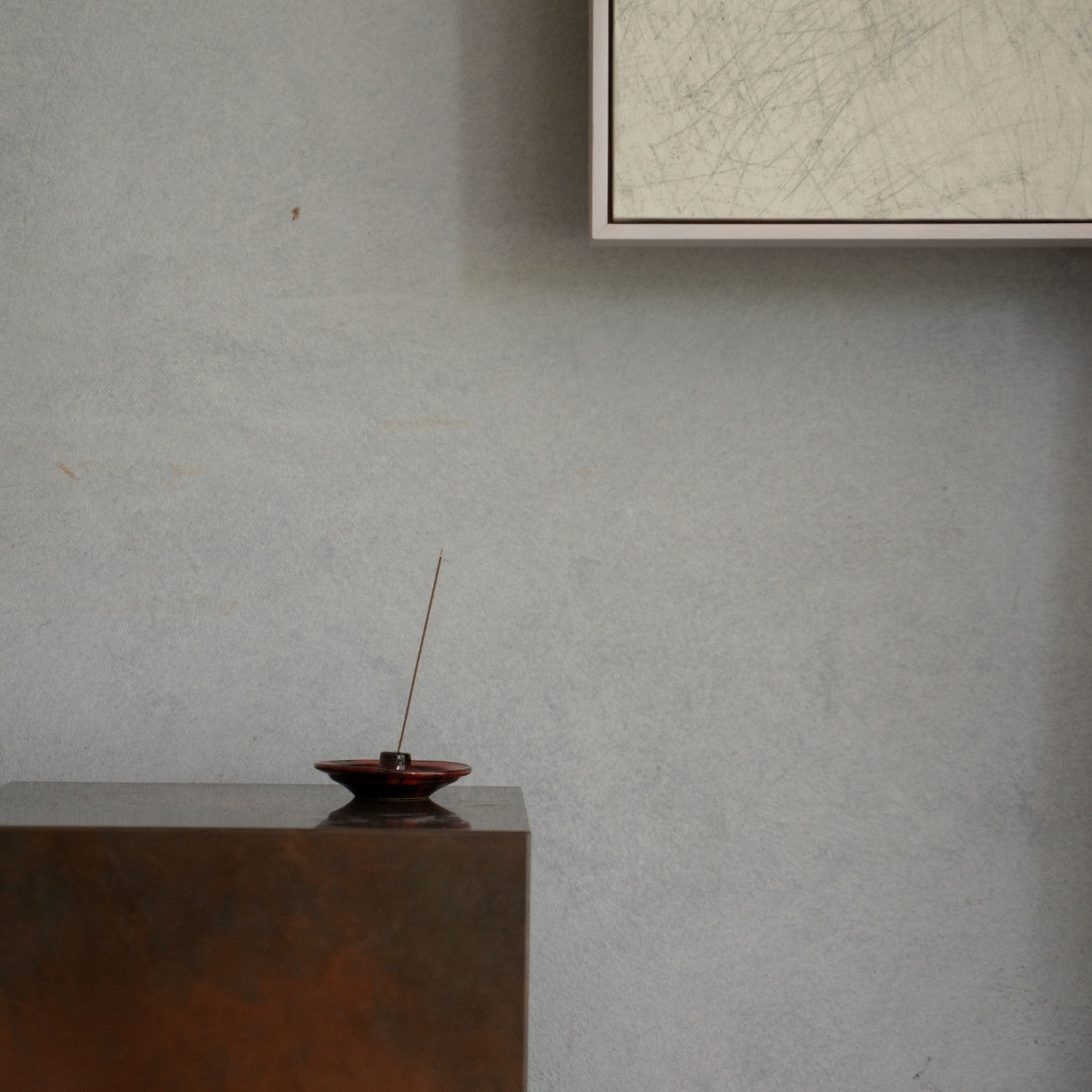 Crimson red Japanese incense holder with a lit stick on a wooden console, setting a serene mood for a meditation routine.