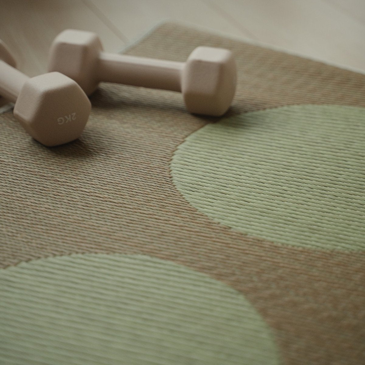 Detailansicht der japanischen Tatami-Yogamatte „Mond“ in Beige, gewebtes Muster aus natürlichem Rattan und eine kleine Hantel.