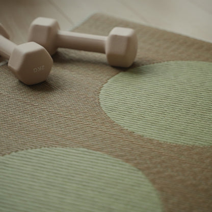 Detailansicht der japanischen Tatami-Yogamatte „Mond“ in Beige, gewebtes Muster aus natürlichem Rattan und eine kleine Hantel.