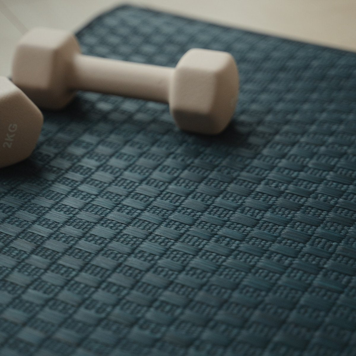 Overhead view of the Japanese Tatami Yoga Mattress "Ed Plain" Navy with dumbbells, showcasing the clean weave and dark border.