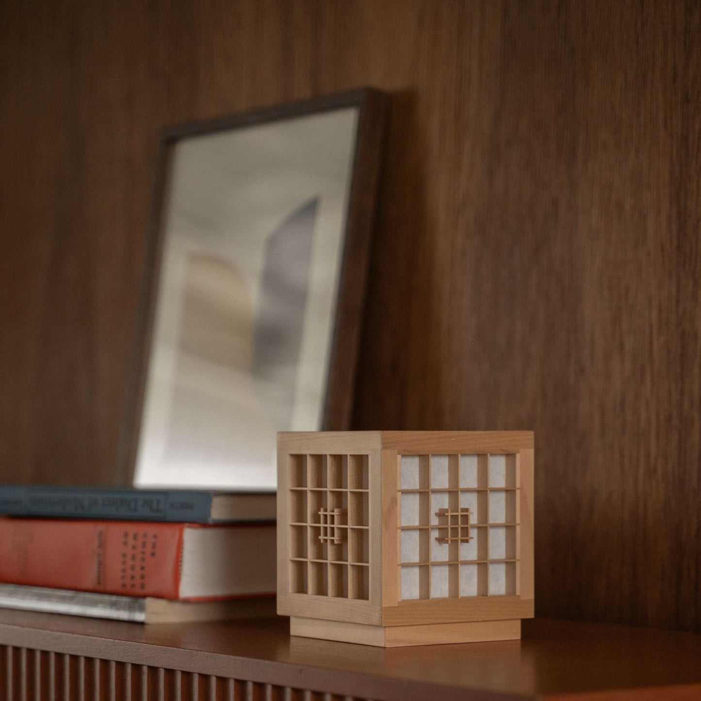 "Lampe de table japonaise en bois « Honoka » utilisée comme lampe d'appoint artisanale de style wabi sabi sur une étagère en bois dans une pièce de style mid-century modern."