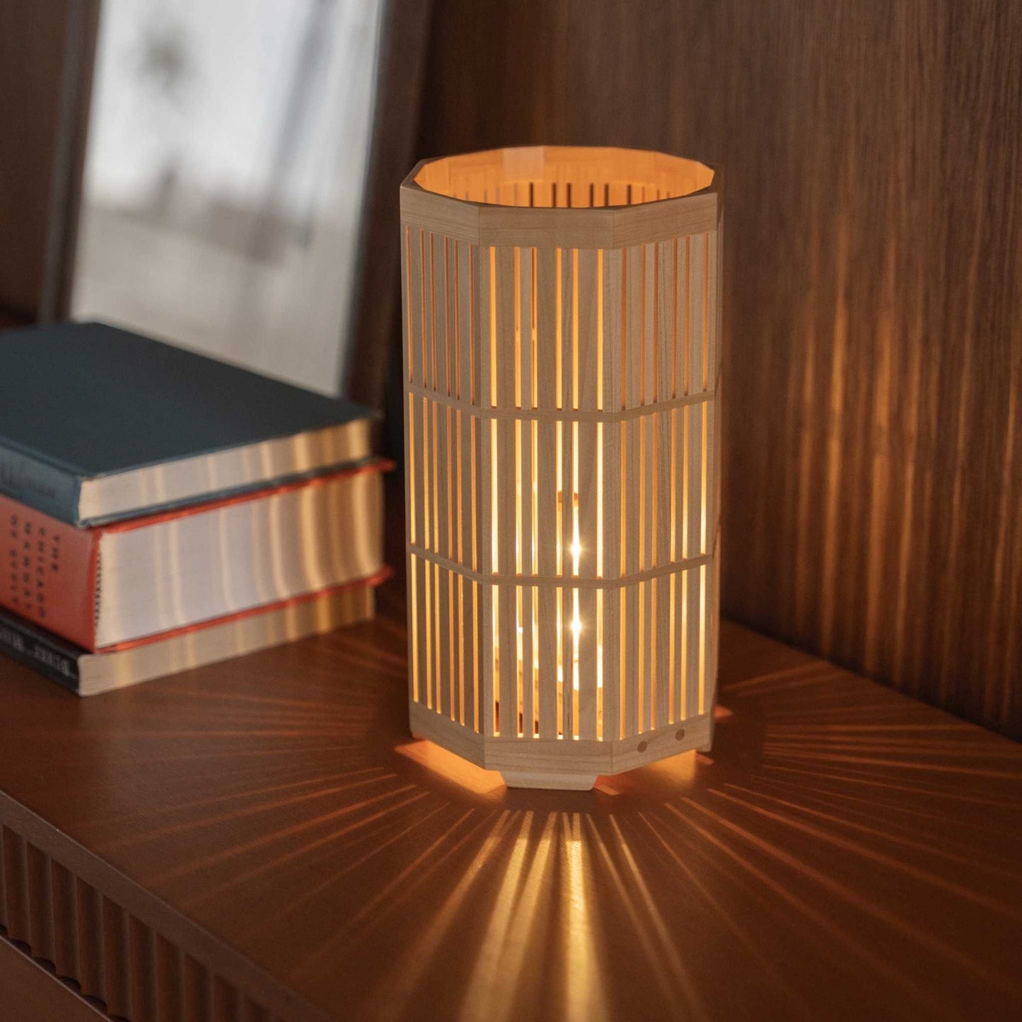 "Lampe de table japonaise en bois Lit "Kagayaki" servant de lampe d'ambiance, projetant des ombres radiales sur une console de style mid-century modern."
