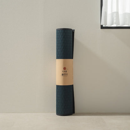 Rolled Japanese Tatami Yoga Mattress "Ed Plain" Navy standing by a bright window, ready for mindful home meditation.