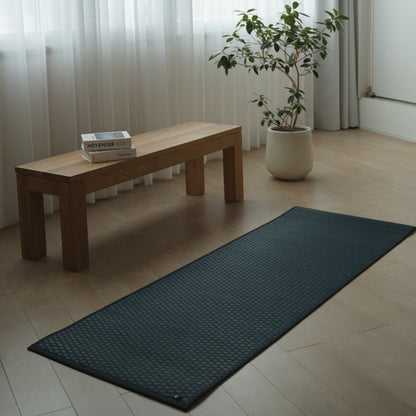 Japanese Tatami Yoga Mattress "Ed Plain" Navy unrolled on a wooden floor in a minimalist living room for a serene home practice.