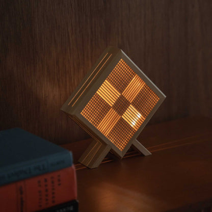 Gros plan d'une lampe de table japonaise en bois allumée "Kanata" servant de lampe d'appoint confortable sur une console de style modern mid-century.