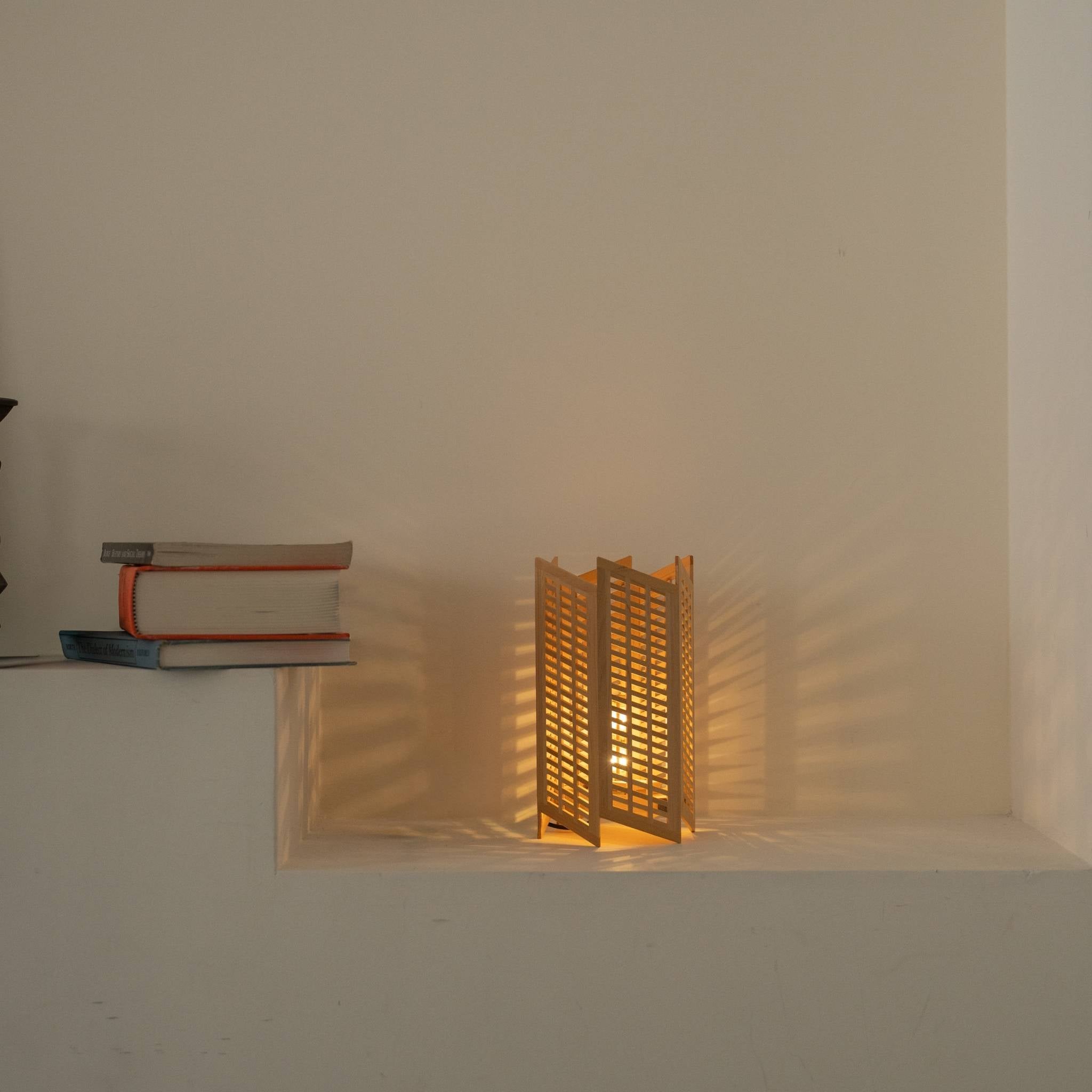 "Lampe de table japonaise Lit « Towaru » servant de lampe d'ambiance, projetant de magnifiques ombres géométriques dans un salon Japandi."