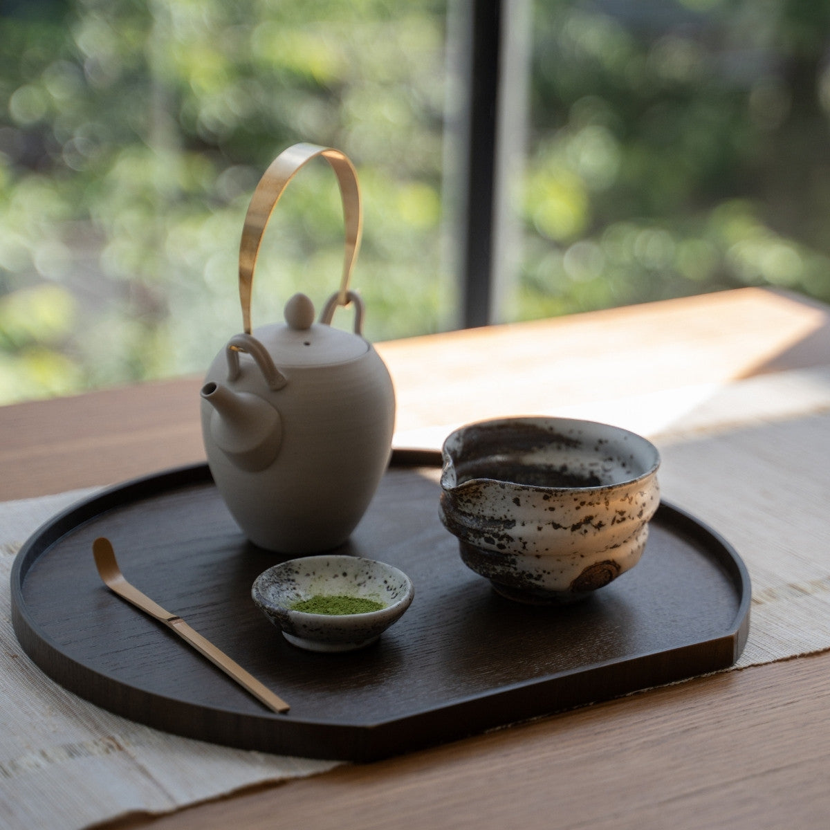 Zui uneven white Japanese matcha bowl with spout and a teapot on a tray by a window, perfect for casual matcha latte making