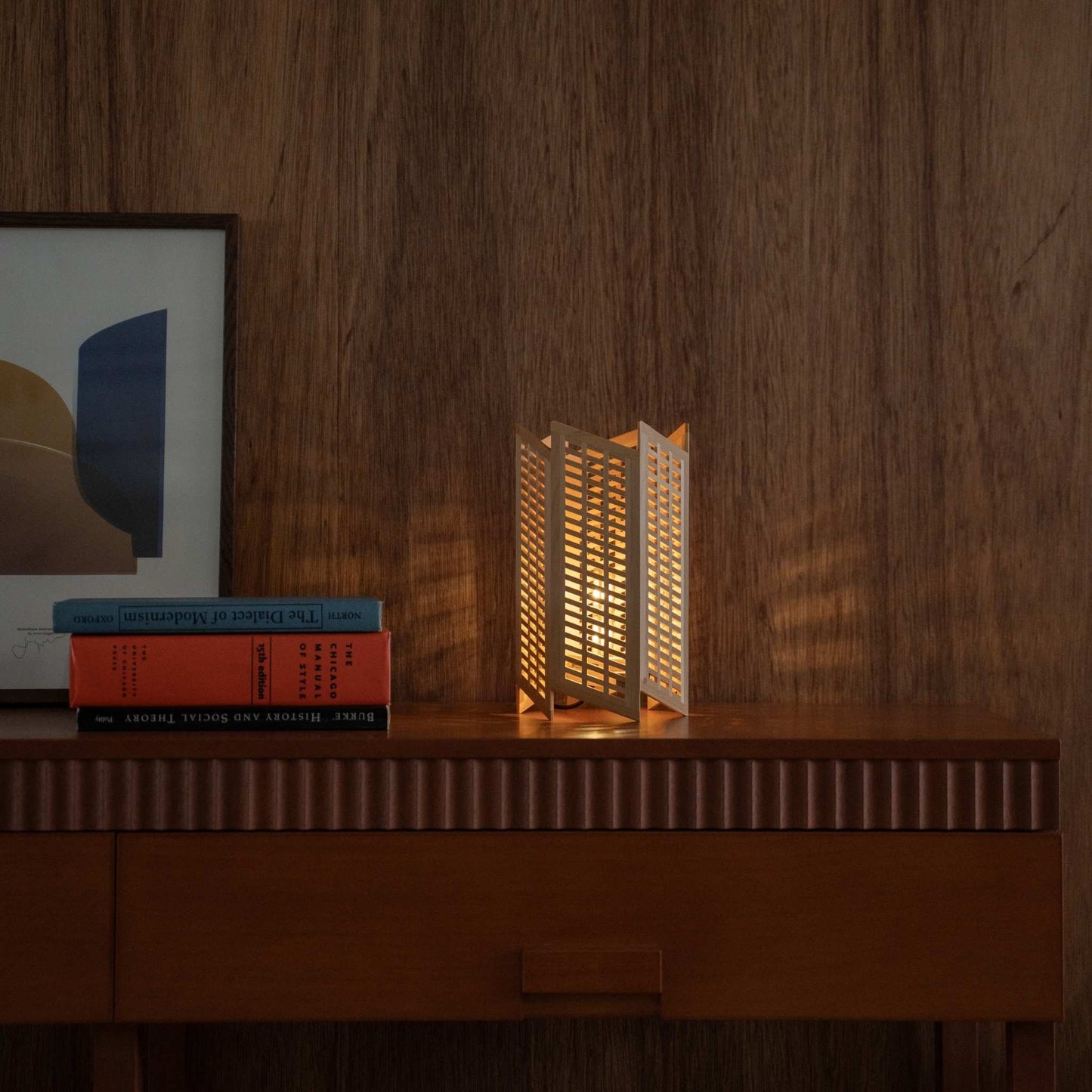 "Lampe de table japonaise en bois « Towaru » projetant des ombres géométriques comme lampe d'ambiance sur une console moderniste du milieu du siècle."