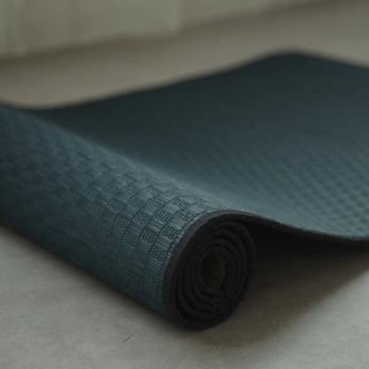 Japanese Tatami Yoga Mattress "Ed Plain" Navy partially rolled on a grey floor, highlighting the solid woven tatami mat texture.