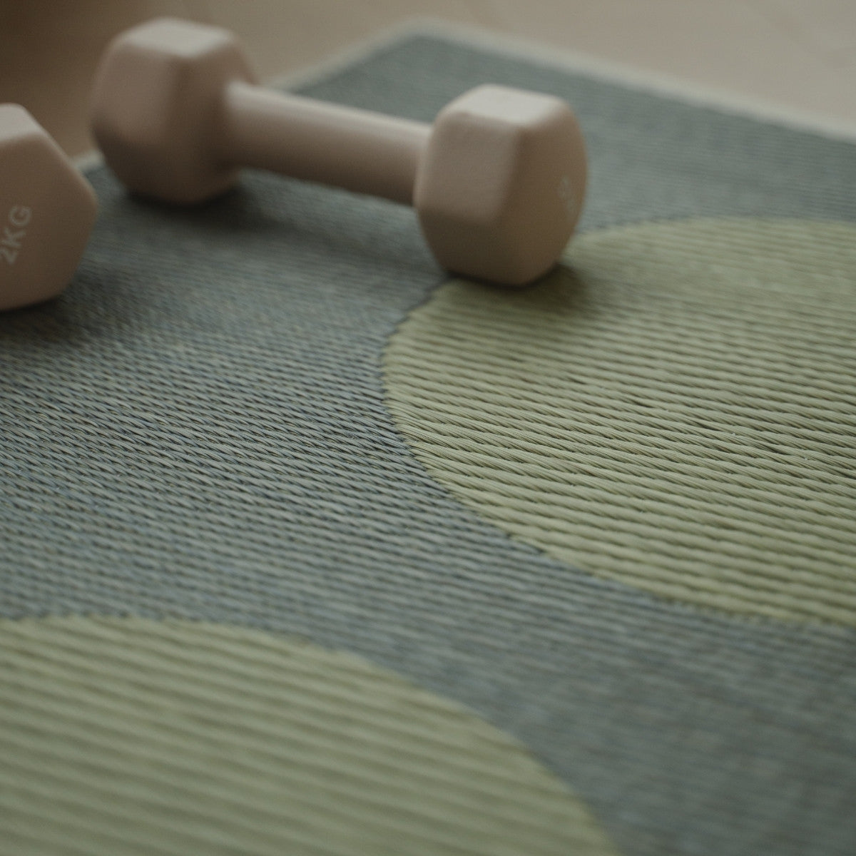 Detailansicht der japanischen Tatami-Yogamatte „Mond“ Grau, mit Fokus auf das natürliche Webmuster aus Binsen und einer kleinen Hantel darauf.