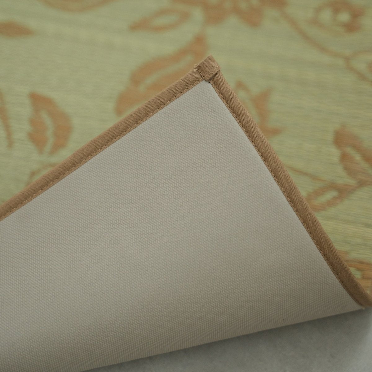 Close-up van de hoek van een Japanse Tatami Yoga Matras "Sarasa" Beige, omgedraaid om de antislip TPE-achterkant en katoenen rand te tonen.