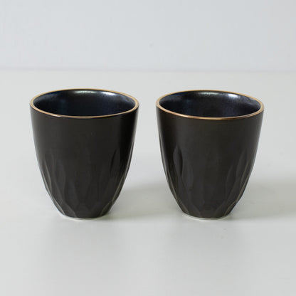 Floral carved sake cups, black porcelain - Two matte black sake cups with gold rims and textured surface