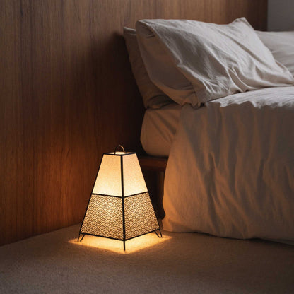 Lit Japanese floor lamp KURA Small casting intricate shadows from its paper shade as an ambient lamp in a Japandi bedroom.