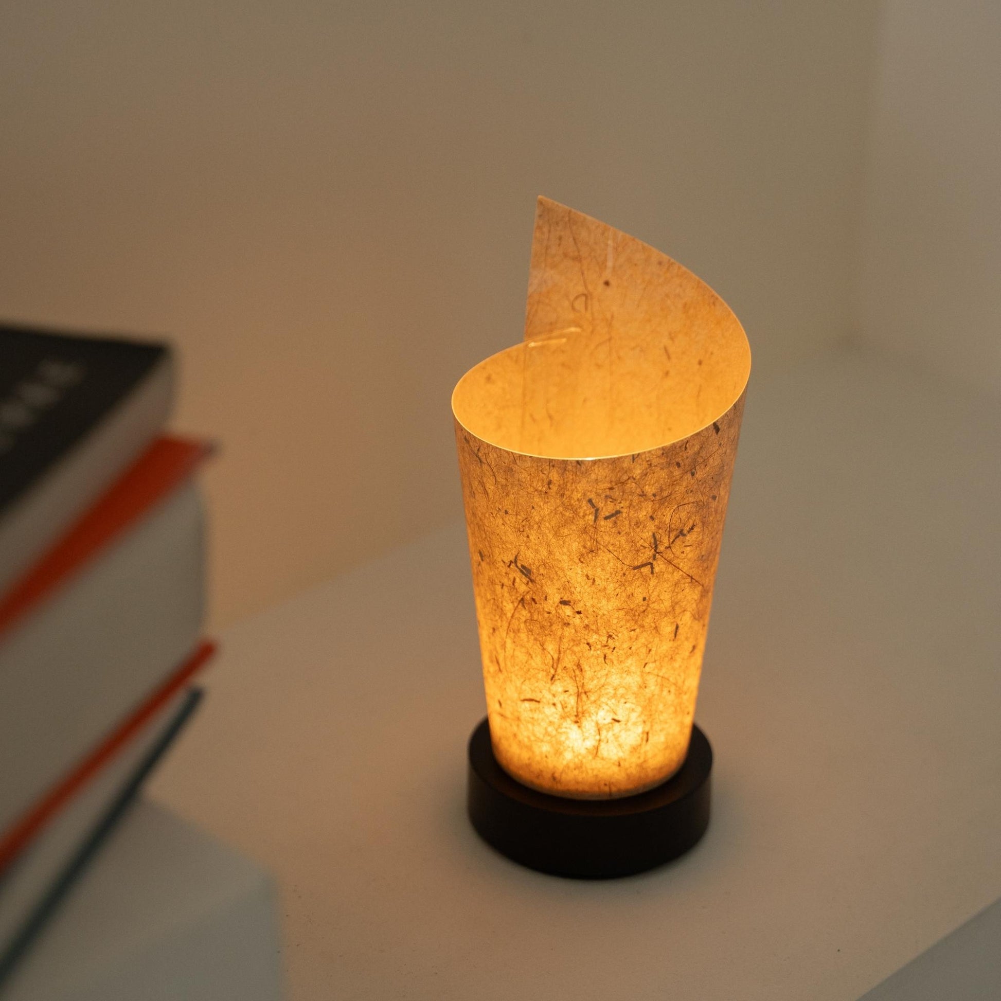 Glowing Japanese paper table lamp "Maki" Cedar Bark revealing rustic paper details and providing a soft glow as a cozy accent lamp.