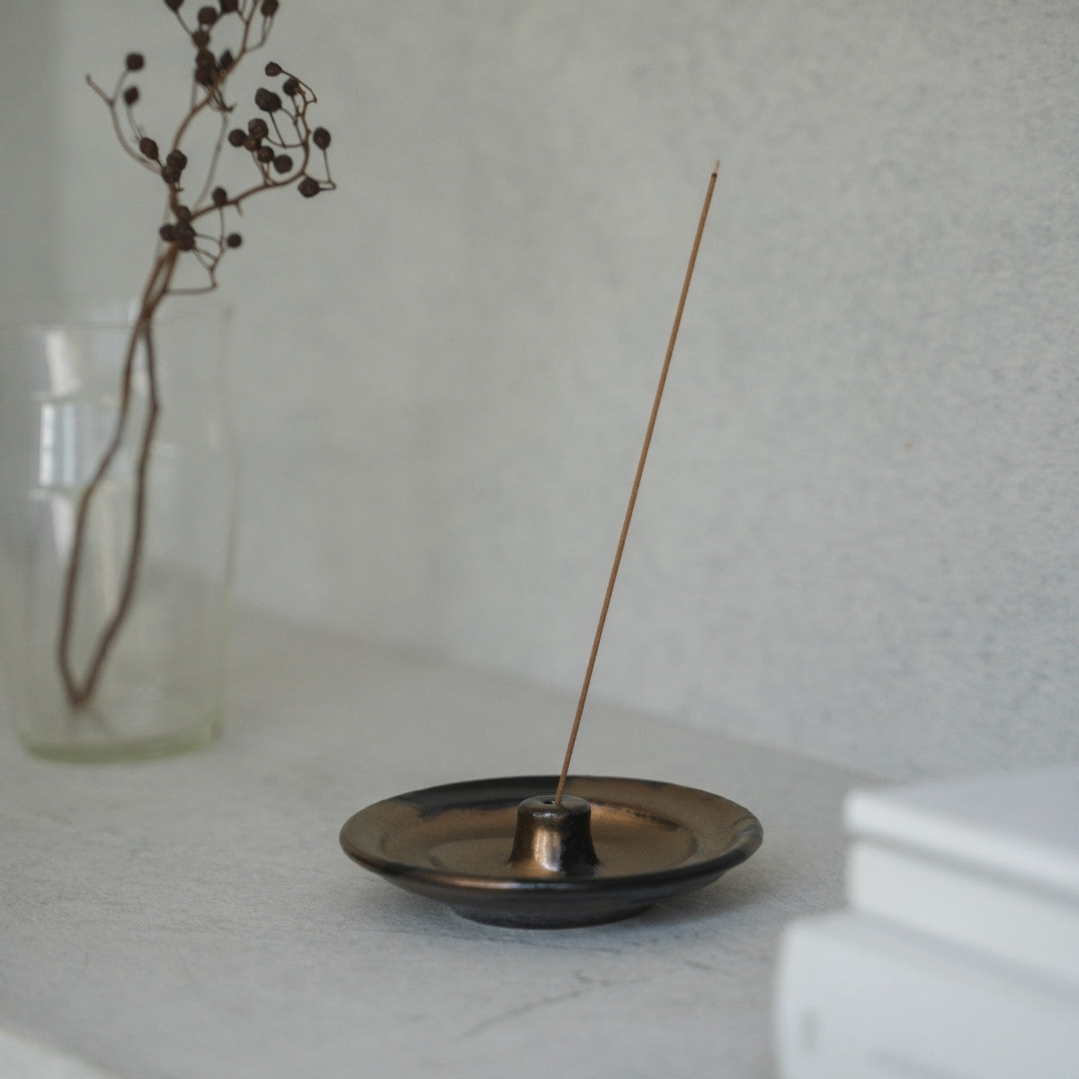 Gold and black Japanese incense holder with a lit stick on a light table, setting a serene mood for morning meditation.