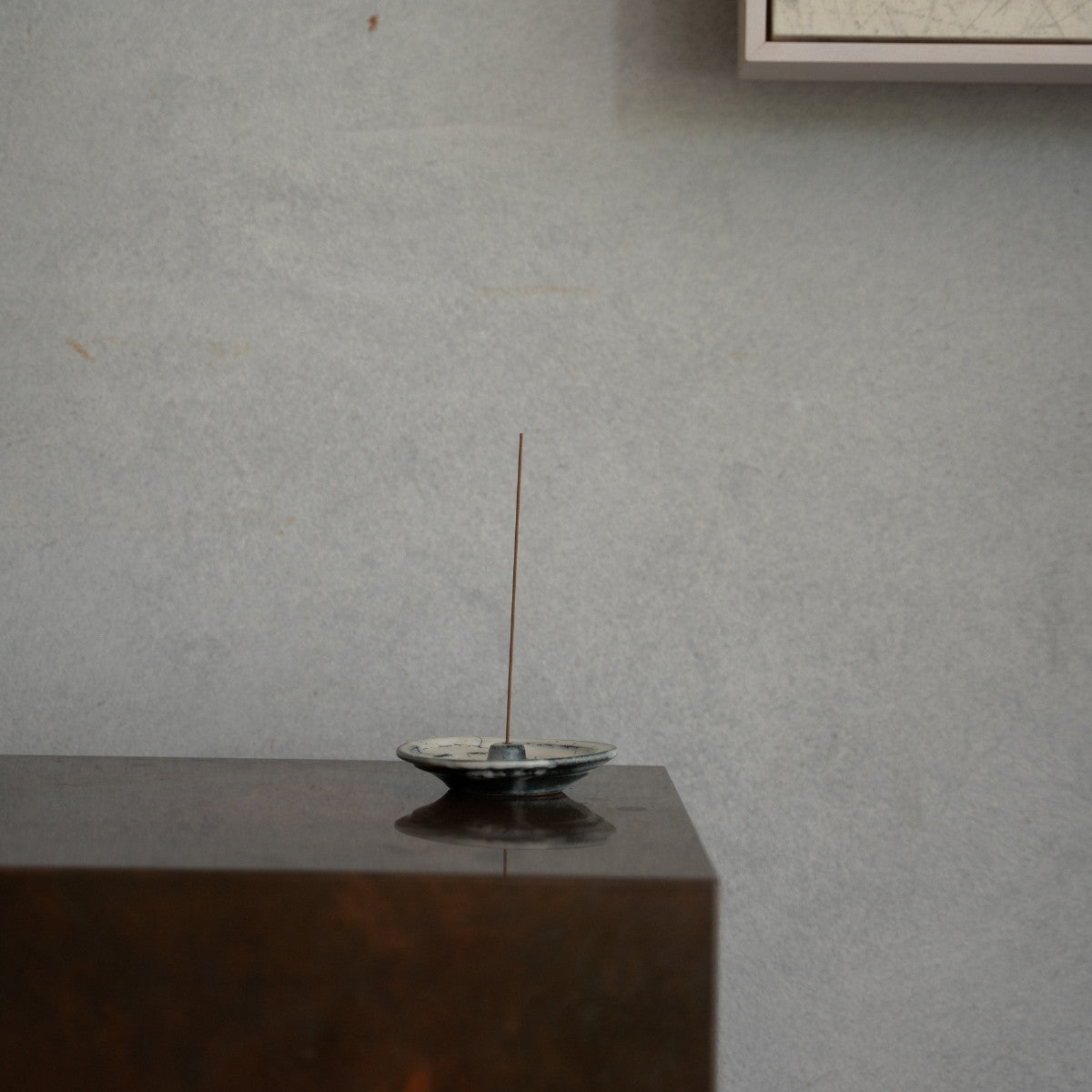 Handcrafted Japanese incense holder on a dark wooden console, setting a calming atmosphere for a daily yoga routine.