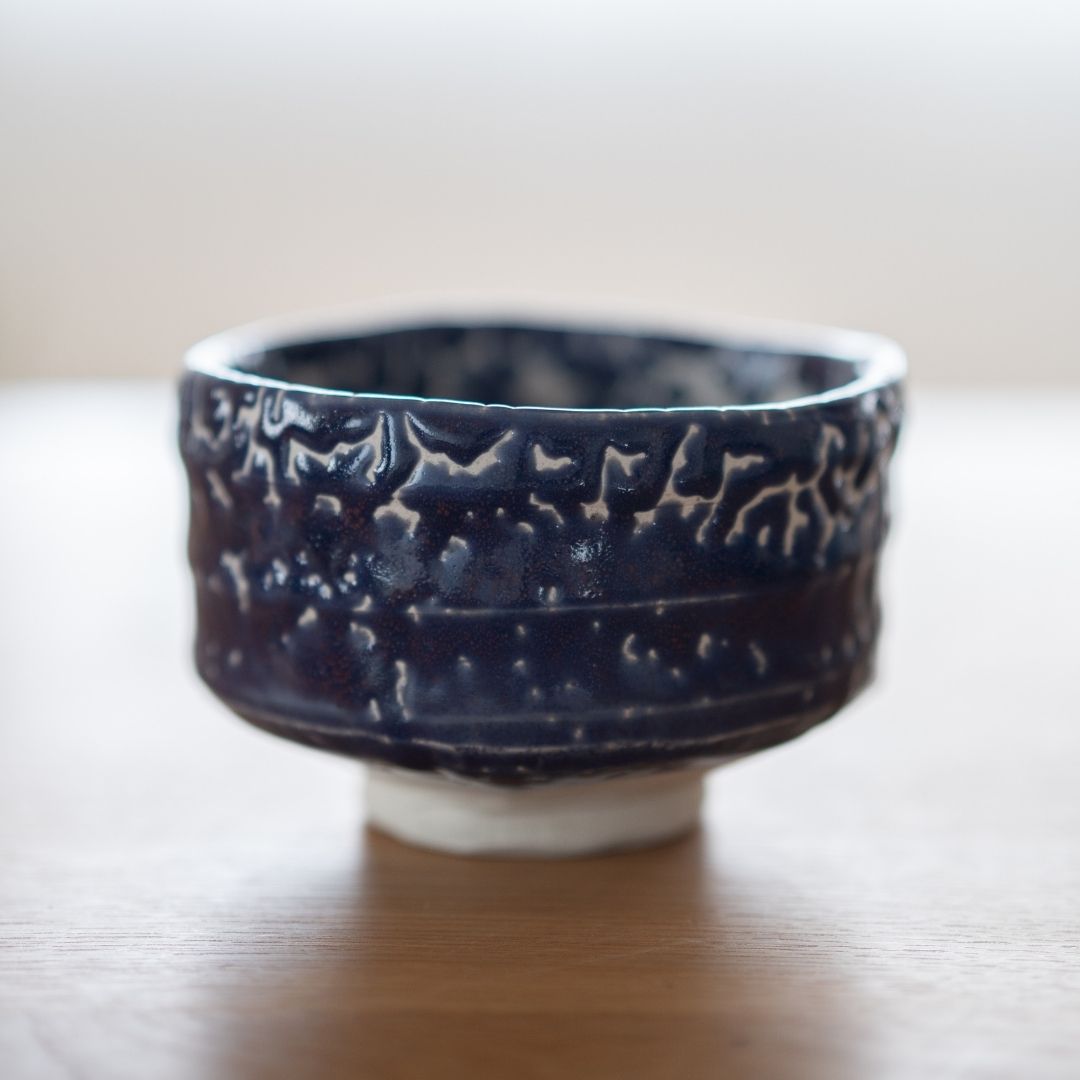 Full profile of the handcrafted Japanese Matcha Bowl "Midnight Blue Kairagi" on a wood table, showing the rough, textured exterior of the traditional Kairagi glaze.