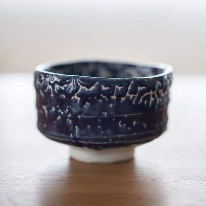 Full profile of the handcrafted Japanese Matcha Bowl "Midnight Blue Kairagi" on a wood table, showing the rough, textured exterior of the traditional Kairagi glaze.