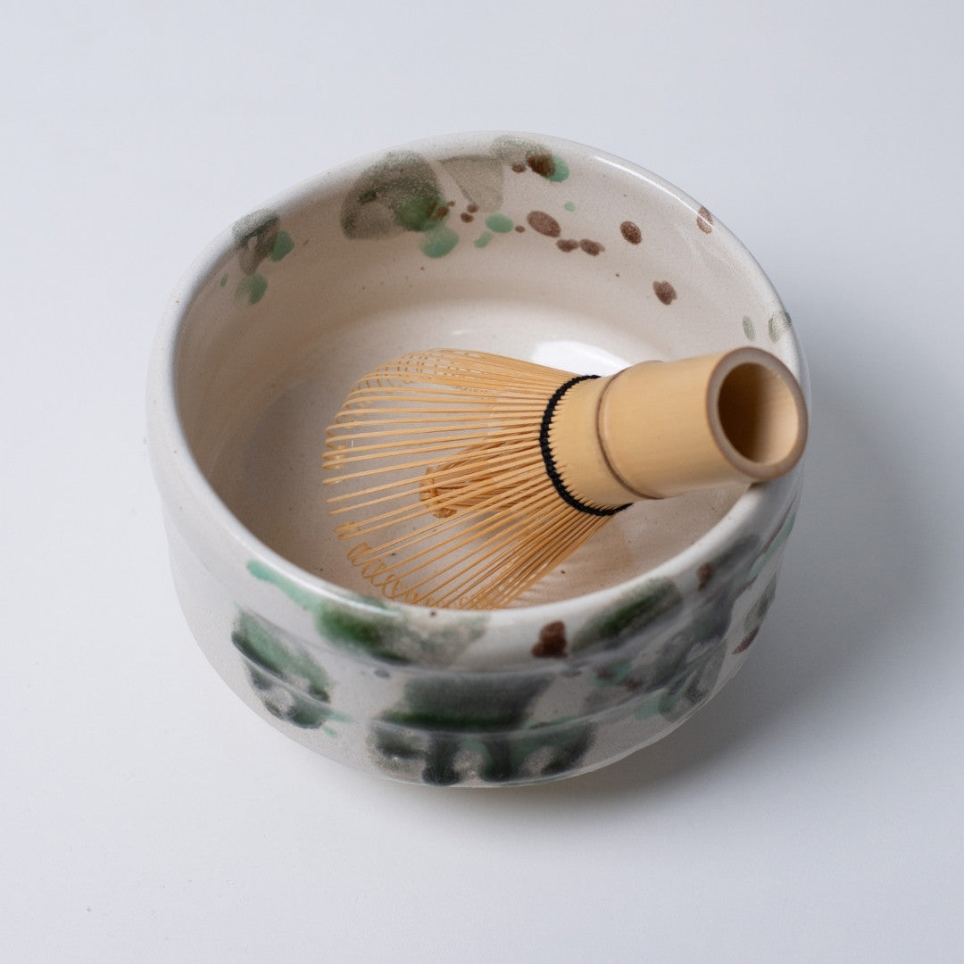 Top view of large Japanese matcha bowl "Forest" with a bamboo whisk, displaying the deep green handcrafted landscape inside the vessel.