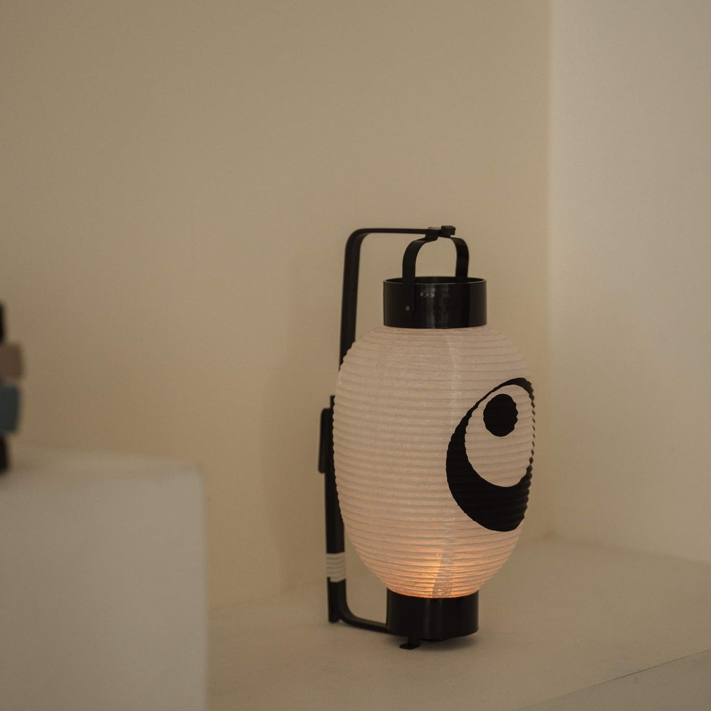 Close up of a handmade washi paper lantern chochin featuring a bold black moon and star design on a white surface.