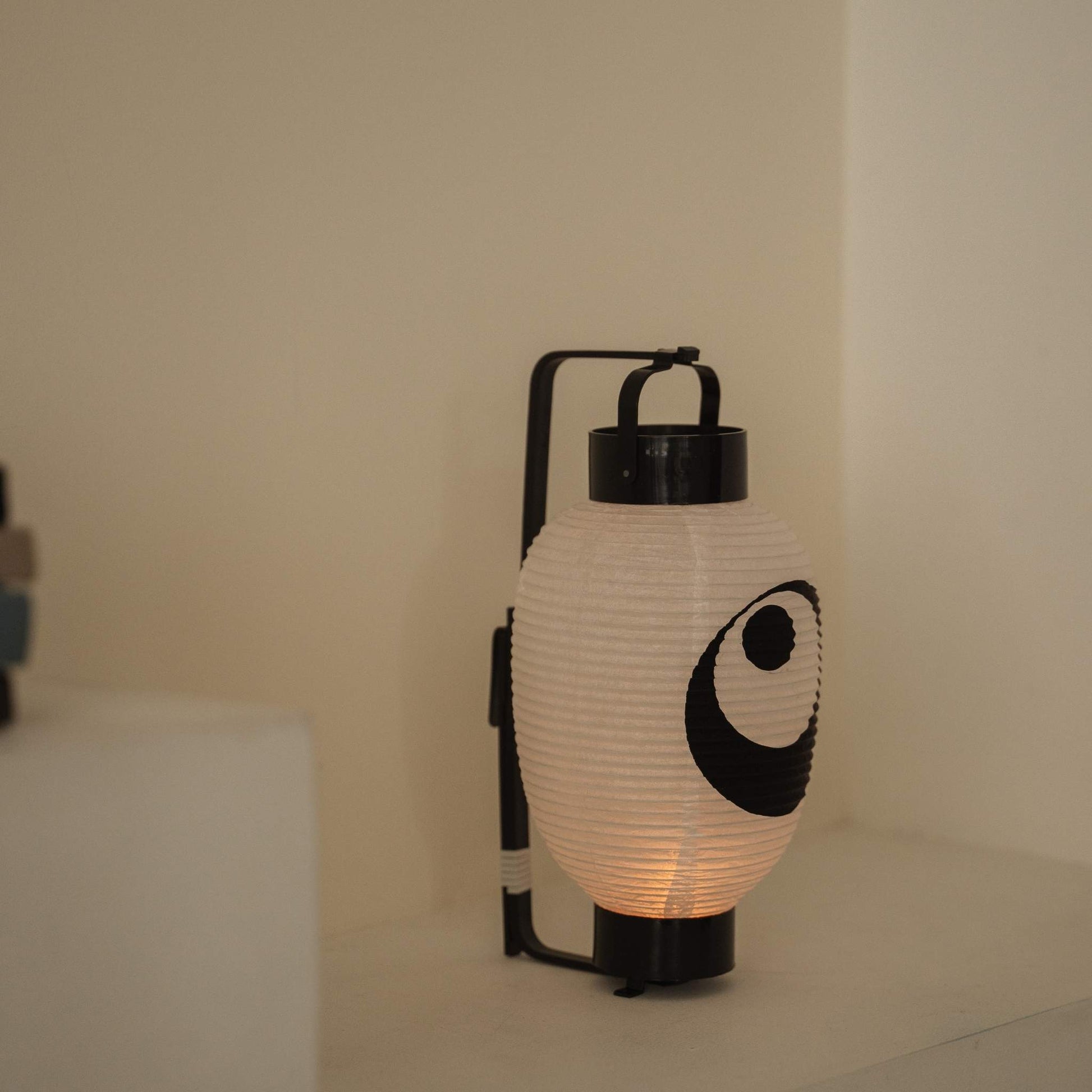 Close up of a handmade washi paper lantern chochin featuring a bold black moon and star design on a white surface.