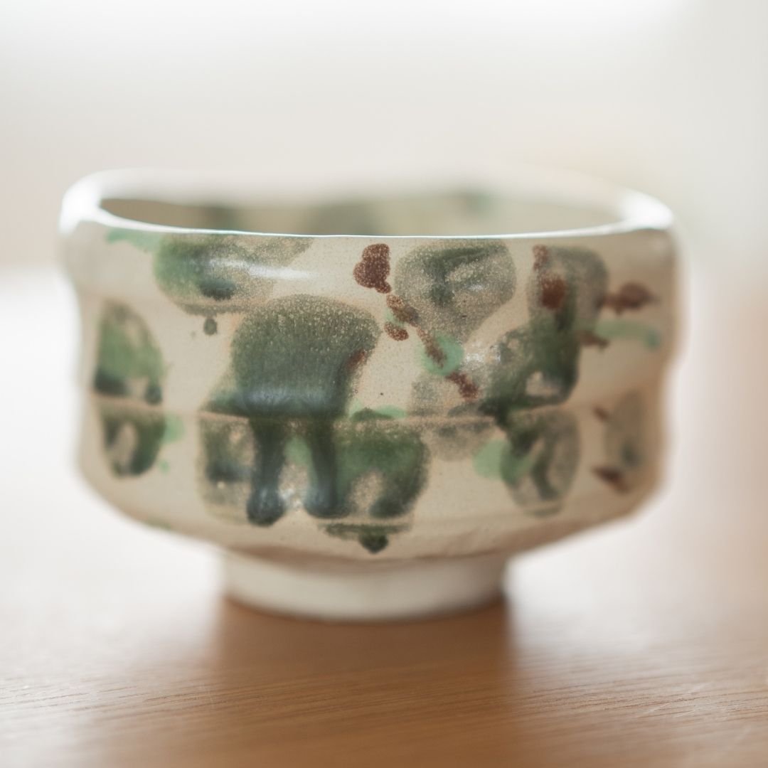 Close-up detail of the "Forest" matcha bowl, highlighting the rough, tactile texture of the pottery and the artistic scattering of green glaze resembling nature's foliage.