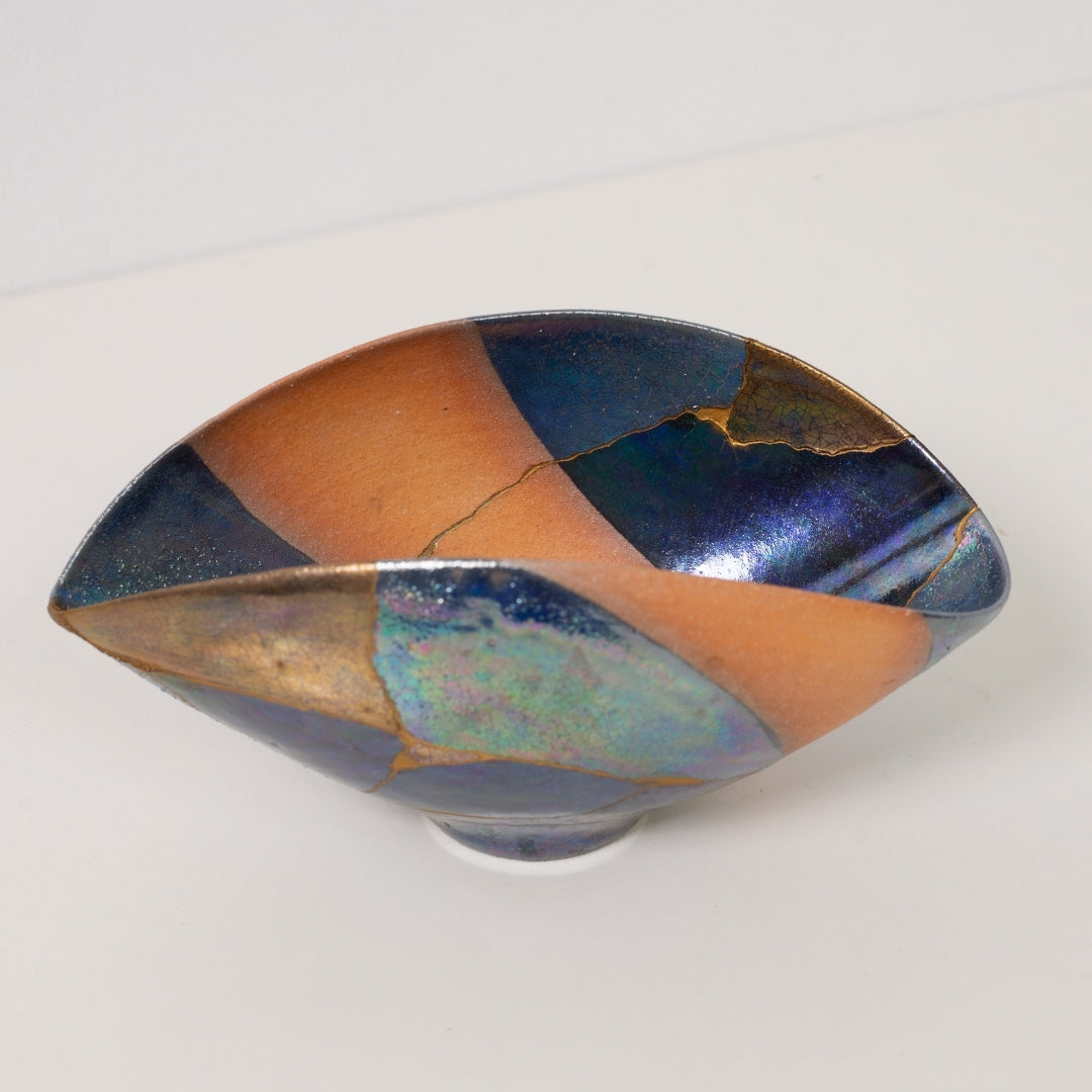 Close up looking into an iridescent kintsugi bowl featuring golden mends that celebrate wabi sabi pottery art