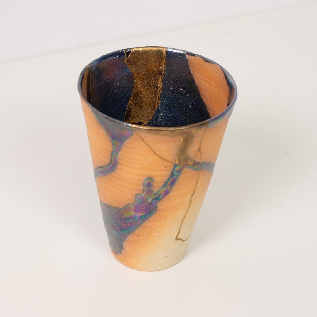 Close up viewing inside a wide kintsugi cup displaying intricate gold lines and dark glazes of traditional pottery art