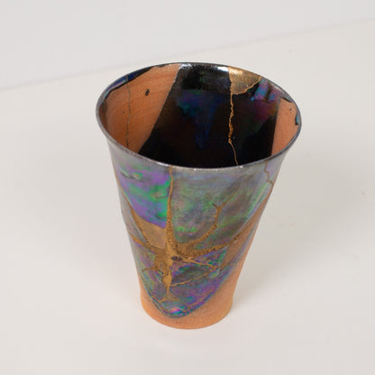 Close up viewing inside a wide kintsugi cup displaying intricate gold lines and dark glazes of traditional pottery art