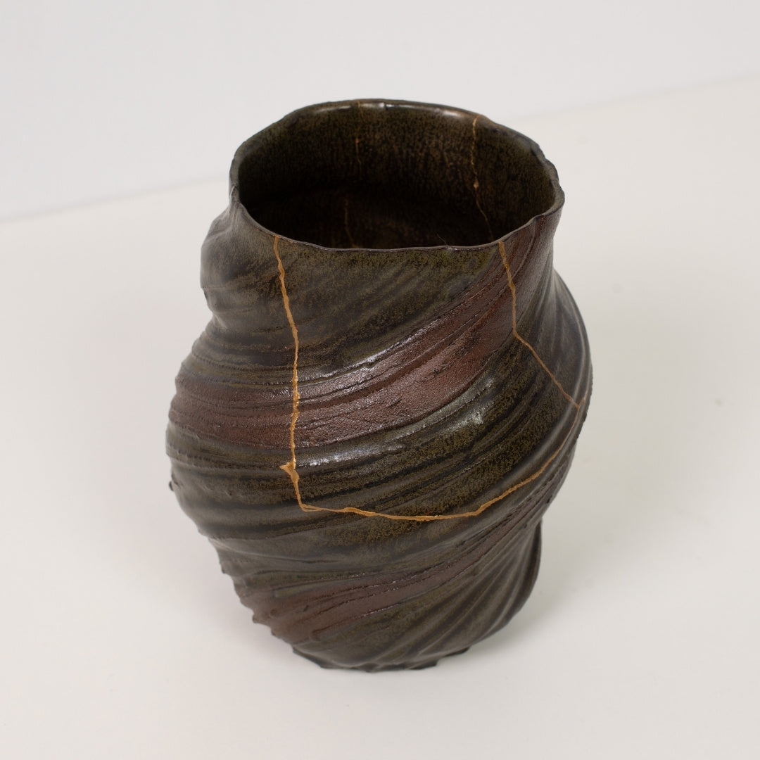 High angle view looking at a textured kintsugi flower vase revealing delicate gold lines that celebrate wabi sabi art