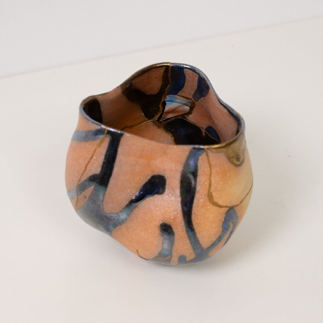 A close high angle view looking inside a colorful kintsugi matcha bowl displaying gold lines and iridescent glazes