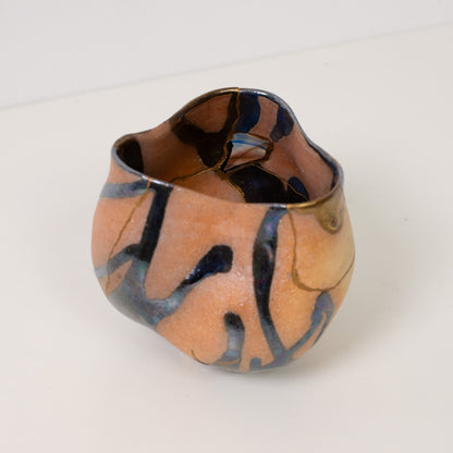 A close high angle view looking inside a colorful kintsugi matcha bowl displaying gold lines and iridescent glazes