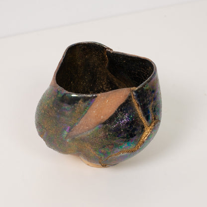 A close high angle view looking into a wider kintsugi matcha bowl showcasing golden veins against dark glazes