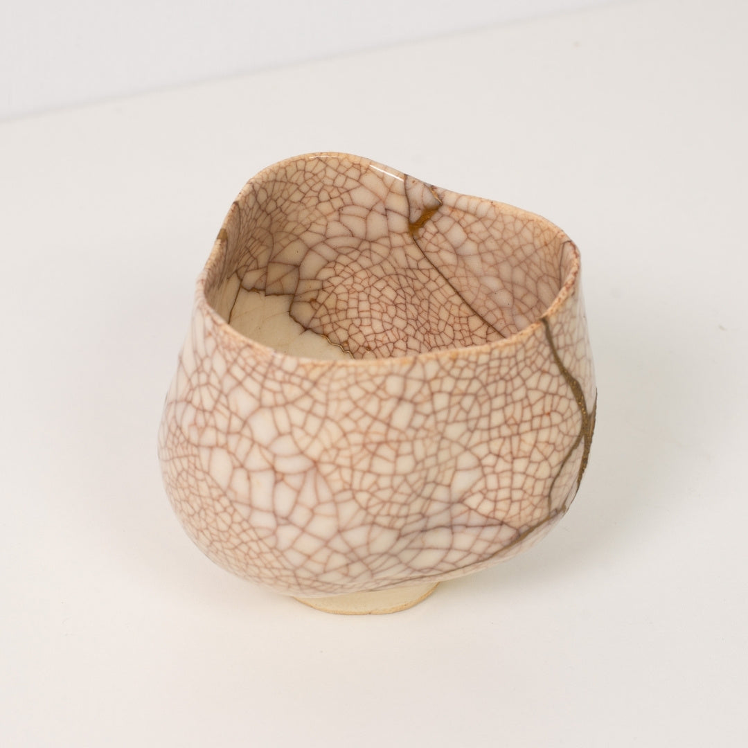 High angle view inside a white crackle kintsugi matcha bowl revealing dramatic golden repairs that embody wabi sabi