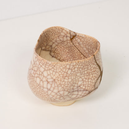 High angle view inside a white crackle kintsugi matcha bowl revealing dramatic golden repairs that embody wabi sabi