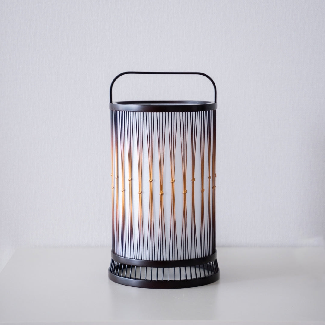 A Japanese bamboo floor lamp placed on a white table.